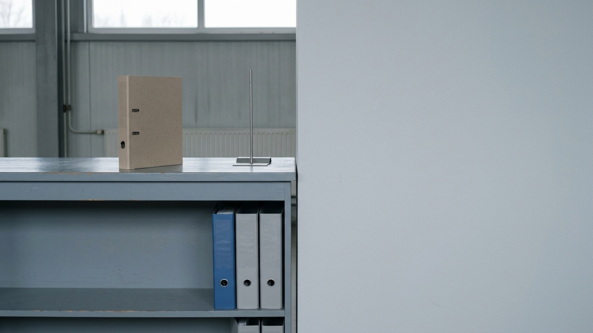 A customs clearance counter in a quiet terminal office, one blue binder among grey ones.